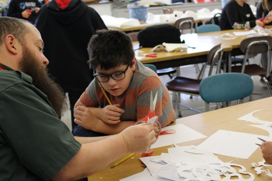 Mr.+Gregg%2C+art+teacher%2C+demonstrates+to+fifth+grader+Sam+Giovengo+how+to+cut+a+snowflake+from+paper+during+art+class.+