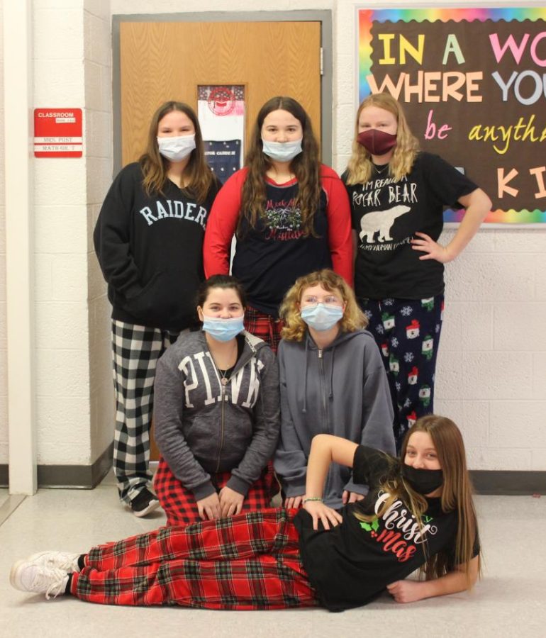 Seventh graders pose in PJs in front of Mrs. Posts room during holiday spirit week. 