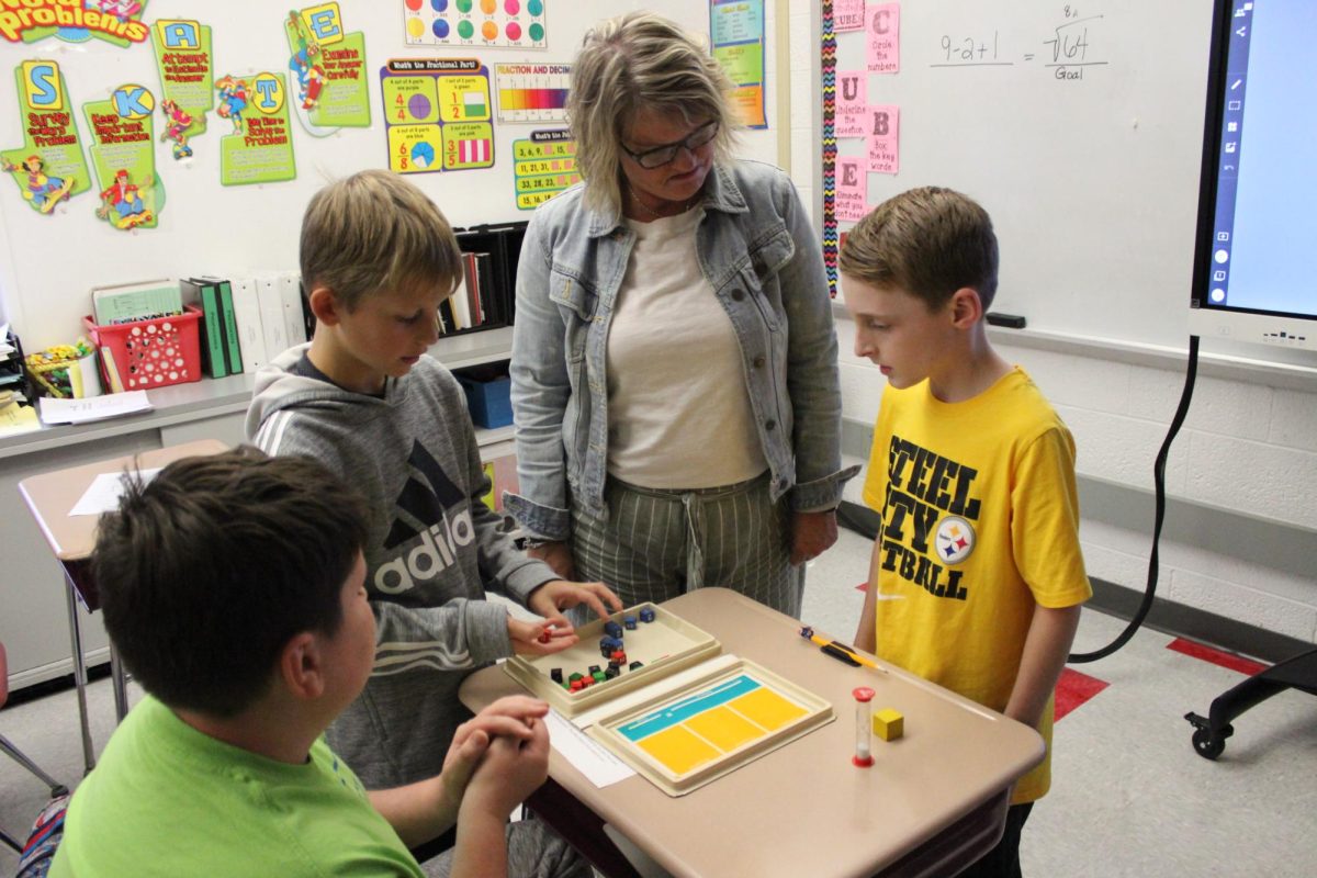 Caption: Mrs. Glover helps students while practicing for the equations competition. 
