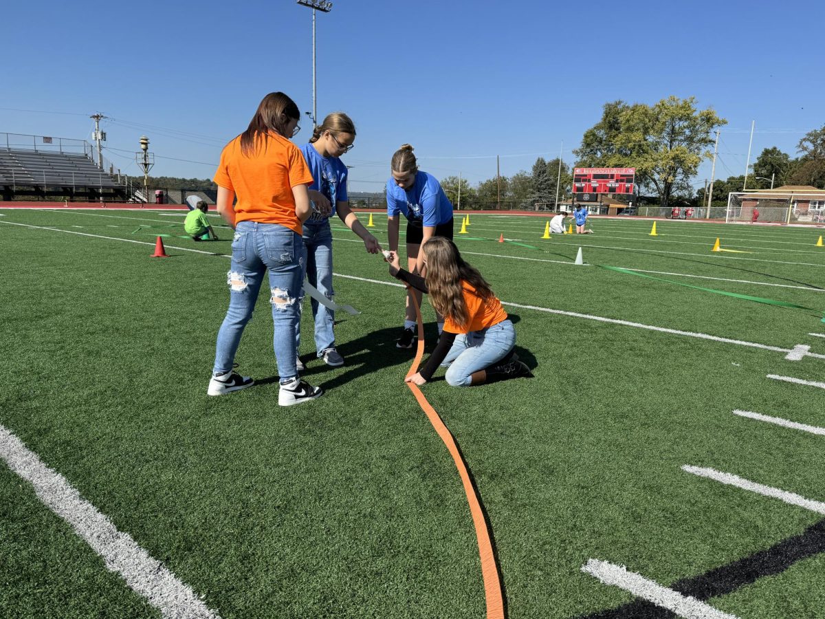 PAWS Ambassadors, Jerah Shiring, Kaylee Anderson, Jacey Lawrence, and Grace Friend, set up streamers to take our 2025 photo on the football field.
