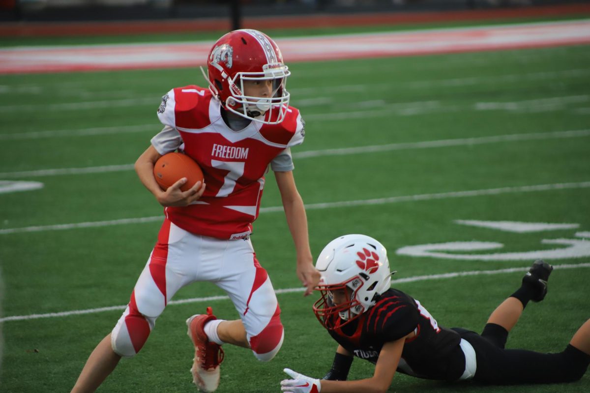 Freedom Little Bulldog Player Kamden Kuntz runs with the football at Freedom’s Stadium trying to get a Touchdown.