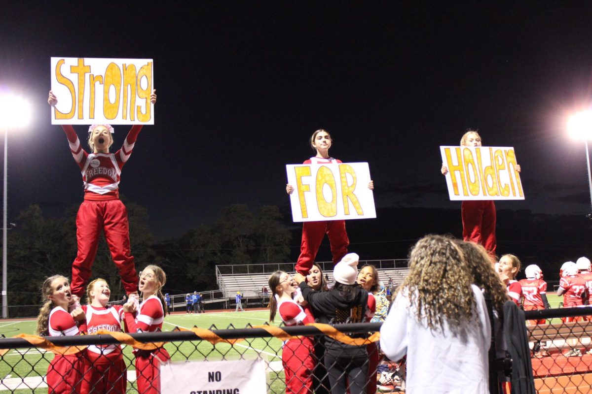 Freedom Junior High cheerleaders lead the crowd in cheers supporting Holden Eckman during the Orange Out game at home on Oct. 16.