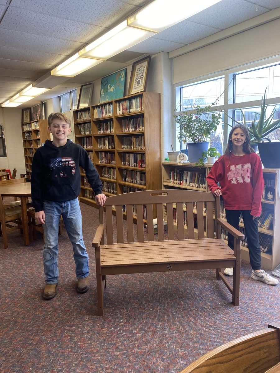 Two sixth graders pose in front of the bench they helped put together.