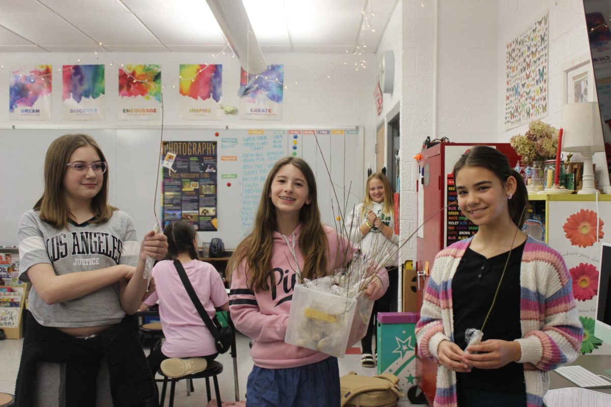 Elana Lehocky passing out little Dogwood trees to Saige Lester and Eva Harper on April 22 (Earth Day).