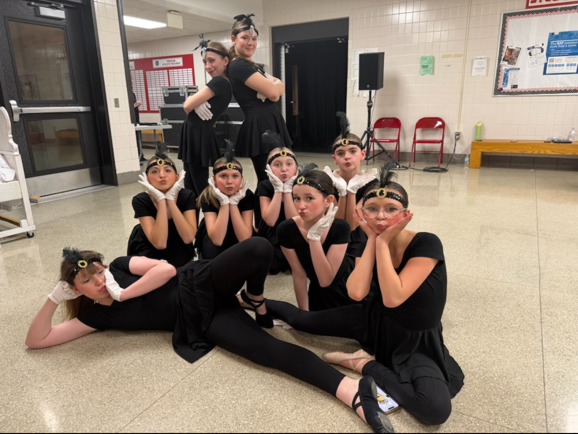 At Freedom Area High School middle schoolers Lydia Bair (6), Greta McNamara (6), Penelope Stroupe (6), Aubrey Capehart (6), Serina Shreckengost (6), Peyton Dalessandro (6), Alice Barns (6), Naomi Kaskalavich (6), and Paisley Nelson (5), are backstage posing for a picture while the cast is on stage giving the audience a Toledo Surprise.