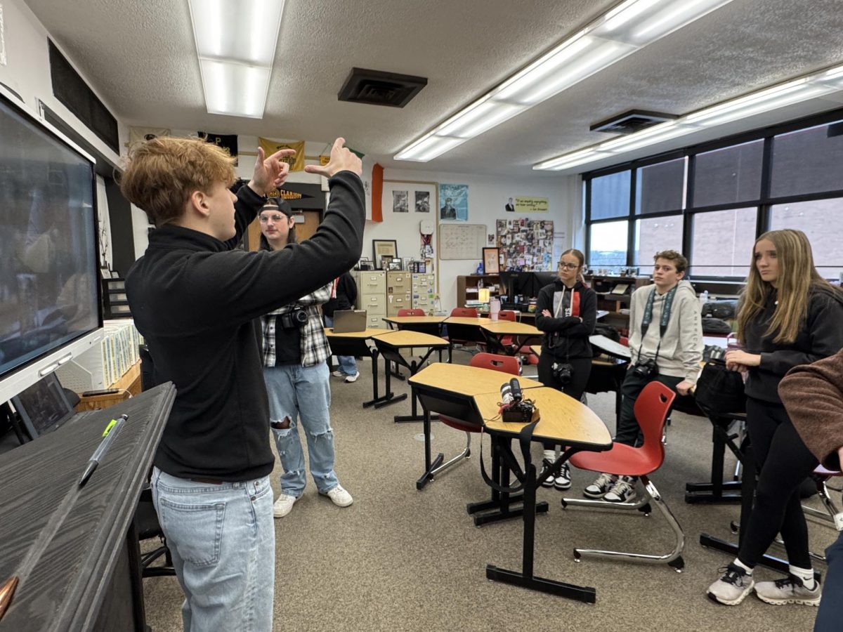 Kaylee Anderson (8), Eli Bruce (8), and Mila Bair (8) watch as Colton Blank (12) and Alex Micon (12) present their slideshow on photography angles.