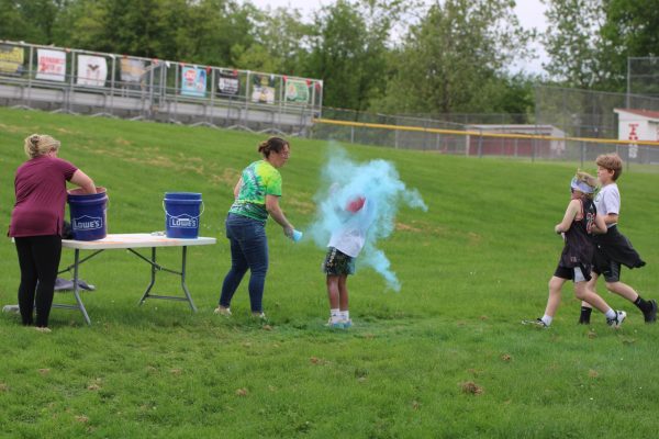A fifth grader gets colored powder thrown on him by Ms. Spencer during the Color Run, on Friday, May 22, in the field.